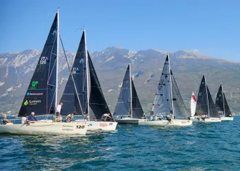 Vele di più imbarcazioni Dolphin in regata sul Lago di Garda con le montagne sullo sfondo