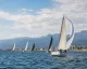 Vele da regata al largo con la costa e i monti sullo sfondo