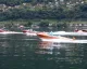 Motoscafi storici Riva in formazione sul Lago Maggiore con riva alberata sullo sfondo