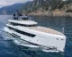 Superyacht bianco a motore in navigazione davanti a una costa rocciosa
