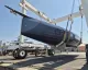 Scafo scuro di uno yacht in carbonio sospeso da una gru nel cantiere