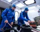 Due membri dell'equipaggio in tute blu che sistemano manovre a bordo di un'imbarcazione da regata