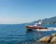 Gommone della Guardia Costiera in navigazione lungo la costa, con scafo arancione e mare calmo