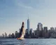 Vela da regata al largo di Lower Manhattan con lo skyline di New York e One World Trade Center sullo sfondo