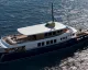 Yacht a largo con sovrastruttura bianca e scafo scuro visto dall'alto