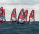 Windsurf con vele arancioni e bandiera italiana in fila su mare mosso sotto un cielo nuvoloso